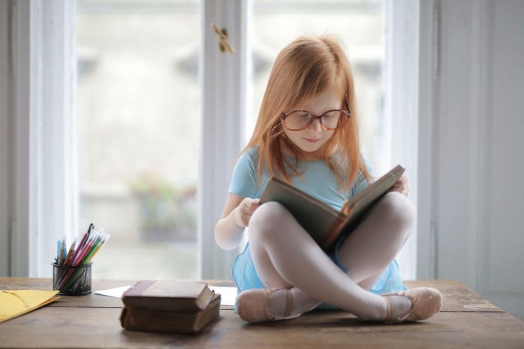 Čítajúce dievčatko sediace na okne